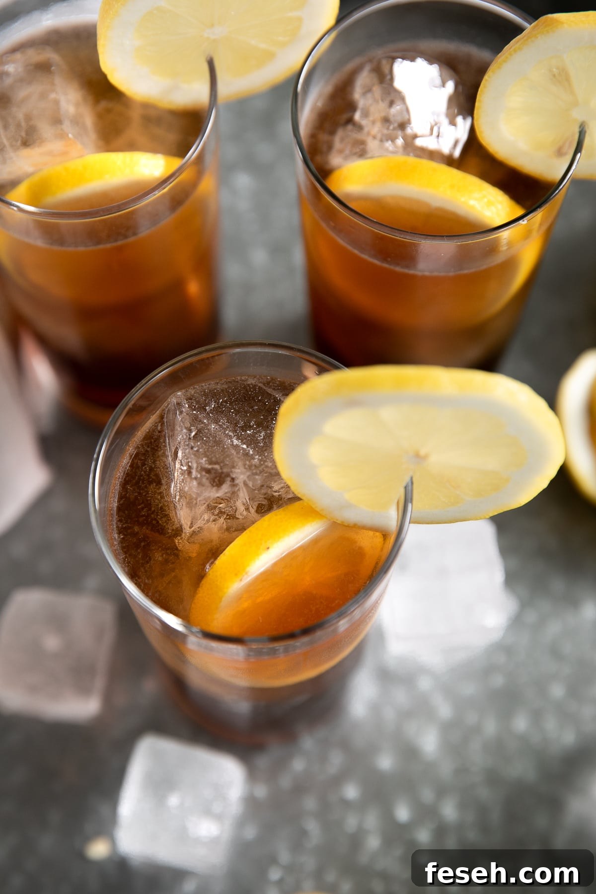 Three Long Island Iced Teas garnished with fresh lemon.