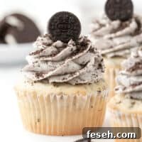 a frosted cookies and cream cupcake topped with Oreo crumbs and a mini Oreo cookie.