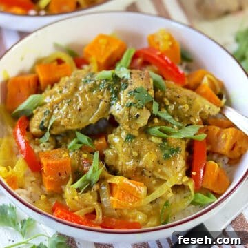Chicken curry in a white bowl garnished with fresh cilantro and sliced green onions.