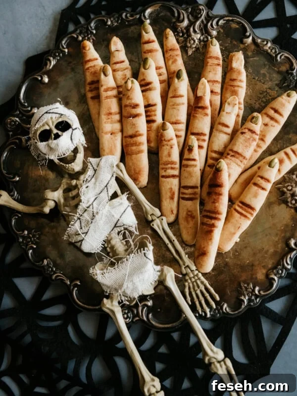 Overhead shot of spooky Witch Finger Cookies on an ornate silver tray with a small mummy skeleton decoration, perfect for Halloween.