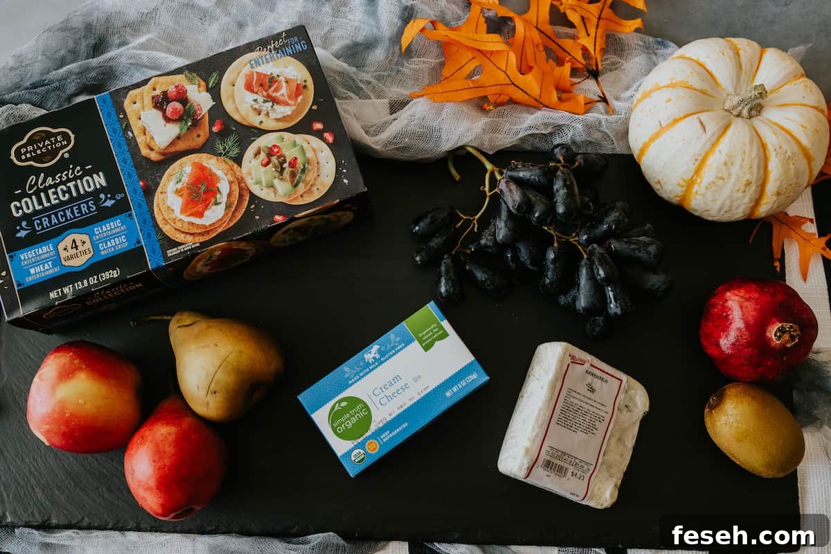 Slate board with crackers, fresh fruit, and cheese arranged and ready to be styled into a Halloween cheese board.