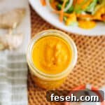 ginger salad dressing stored in a mason jar with a dressed salad in a shallow white bowl.