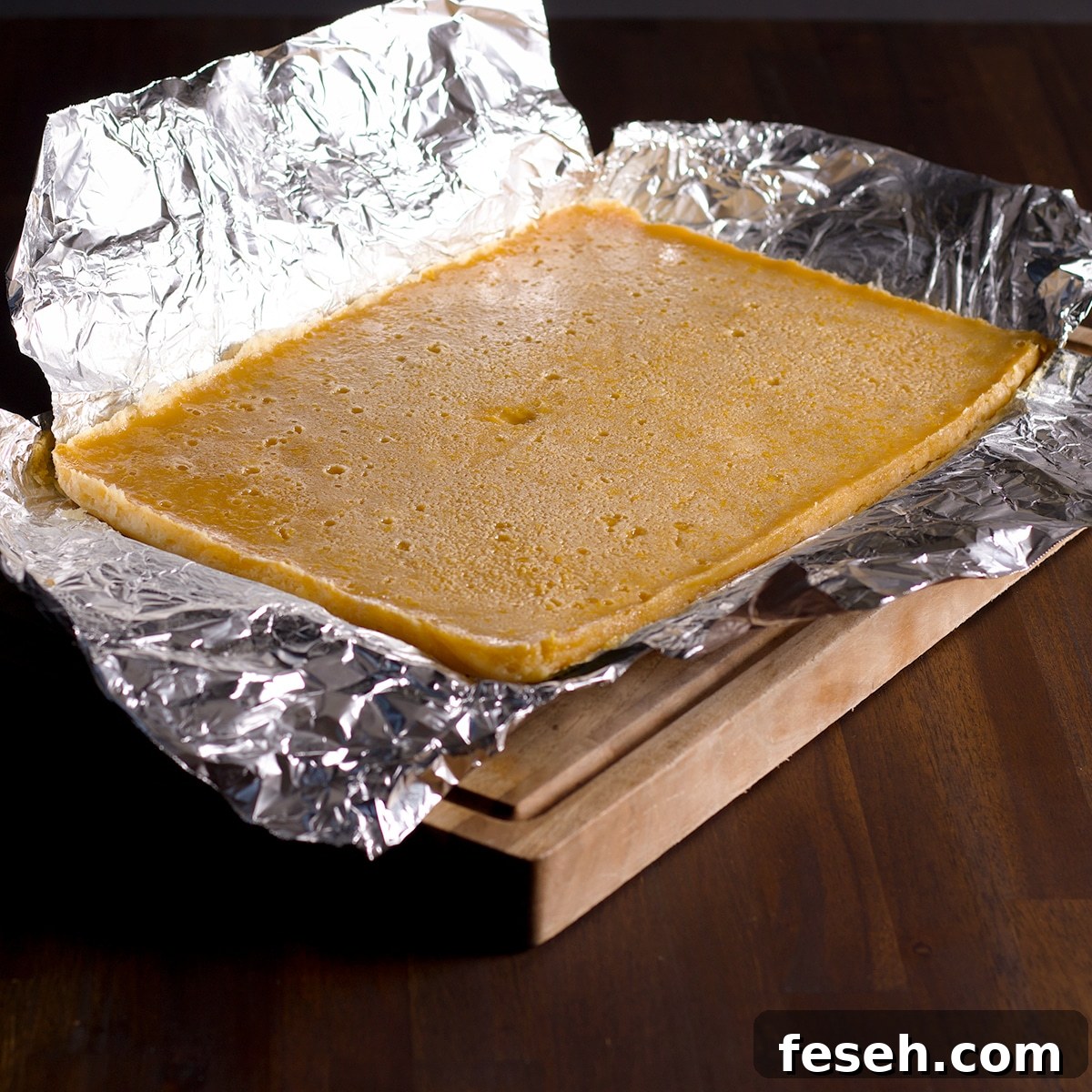 Use the foil to pull the lemon bar cake out of the pan and set it on a cutting board. 