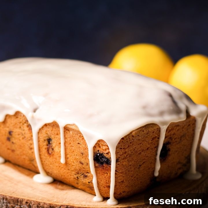 A blueberry loaf cake covered in lemon icing on a wood serving tray.