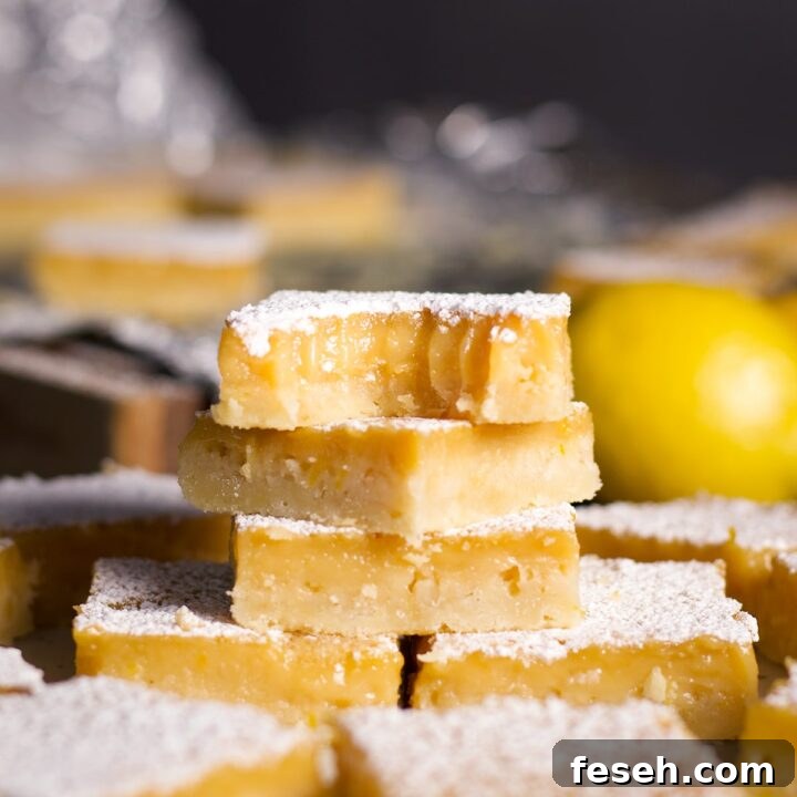 A stack of lemon bars on a plate with a bite taken out of the bar on the top of the stack.