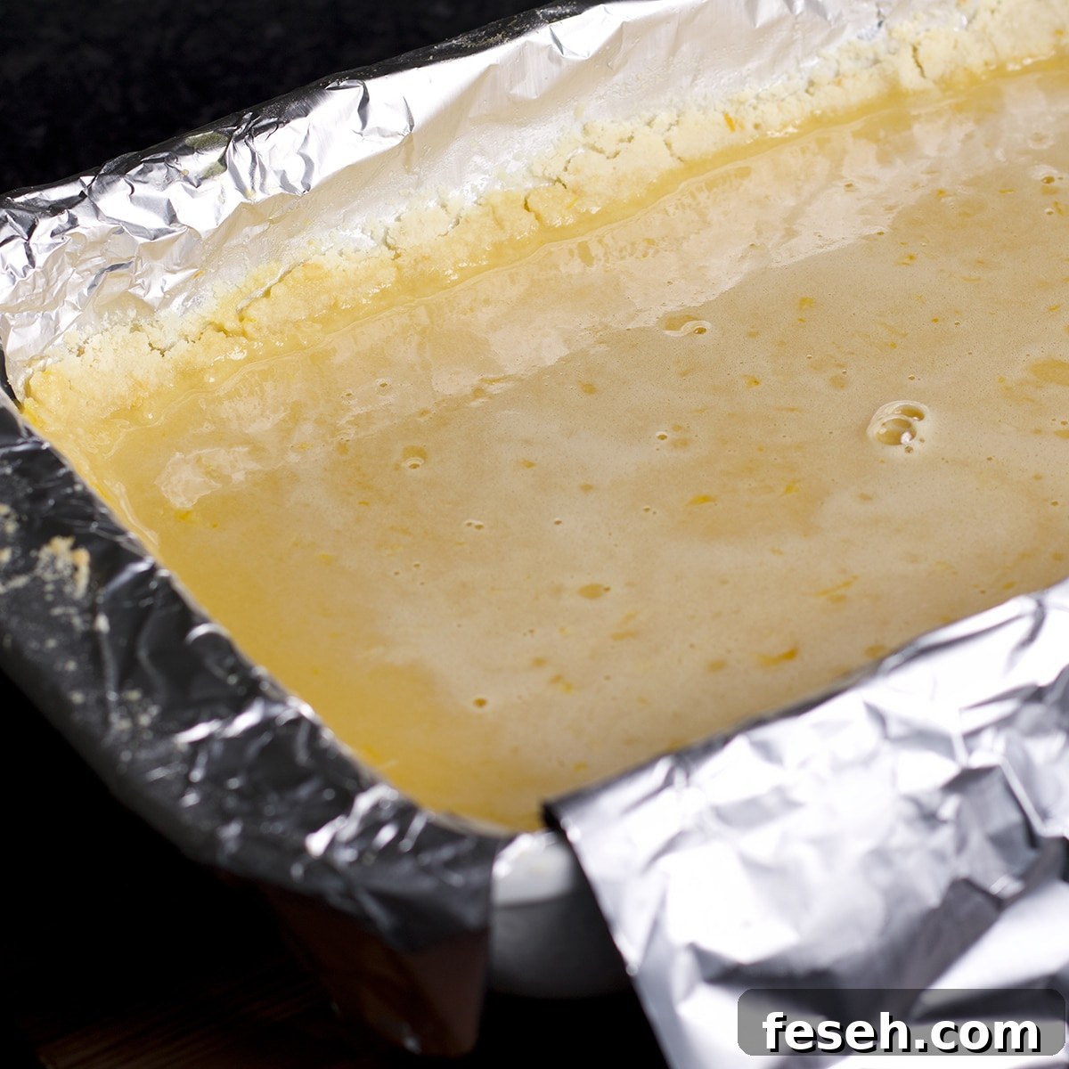 Pouring the lemon bar filling over the shortbread crust.
