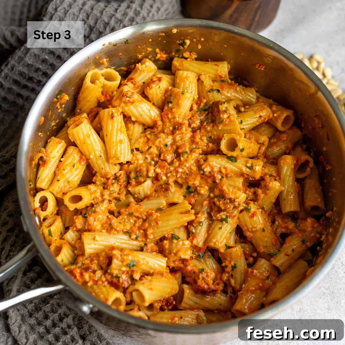 Sauce pan with pasta and red pepper pesto mixed in.