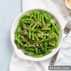 An overhead image of beans poriyal (Indian Stir Fry Beans) in a serving bowl with a fork on the side.