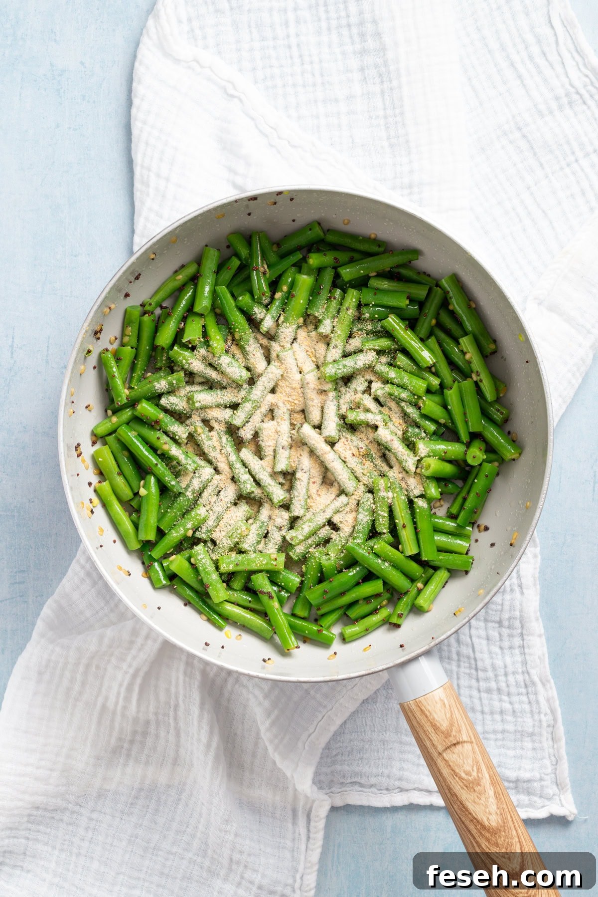 An overhead image of green beans on the skillet with the spice mix on top.