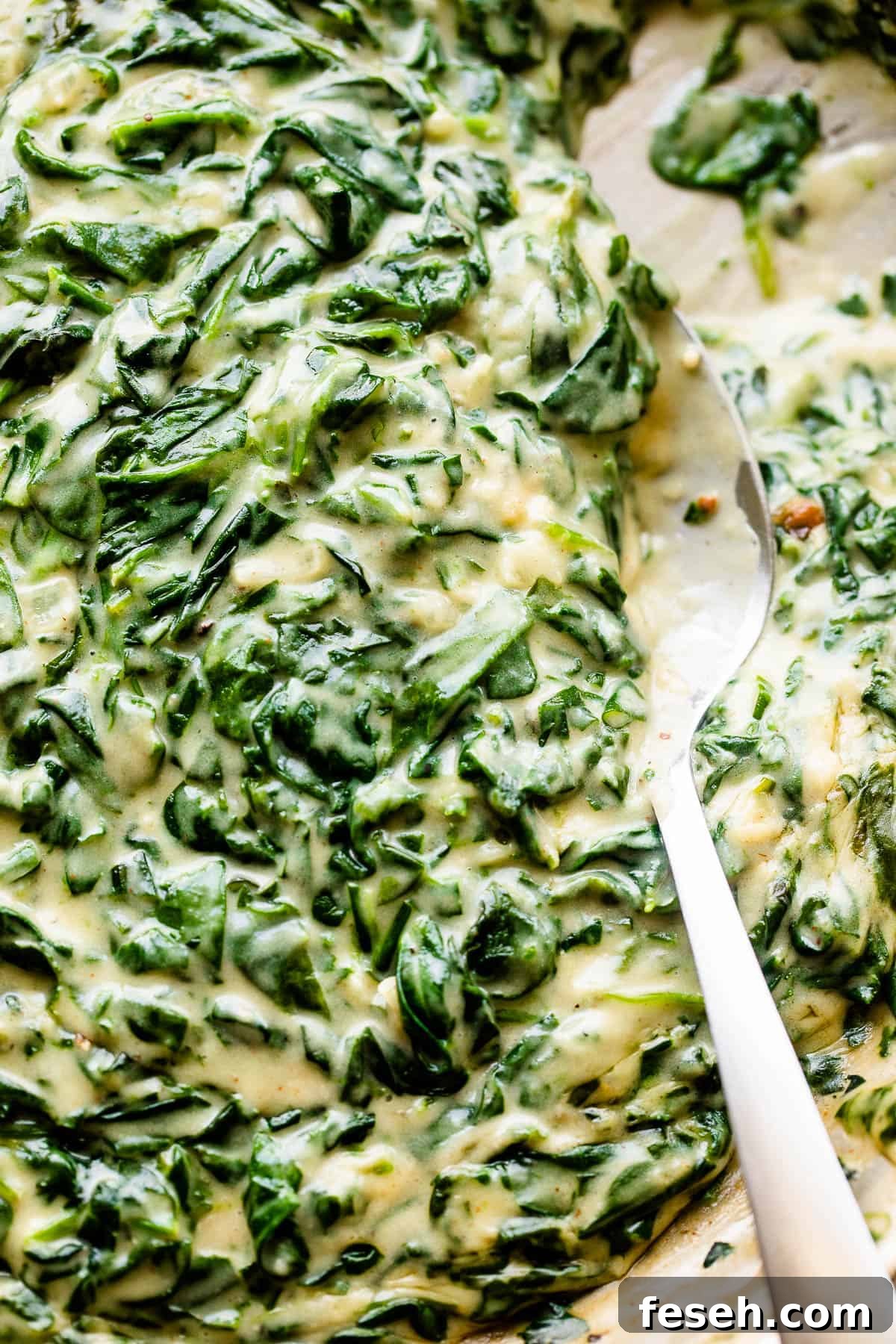 Stirring creamed spinach with a large spoon.