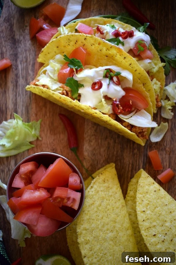Tacos on a wooden board with extra shells and tomatoes