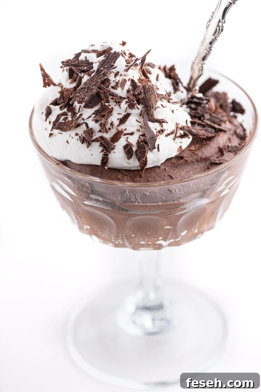 Keto chocolate mousse in a crystal stemmed serving dish with a dollop of fresh whip cream and dark chocolate shavings. 