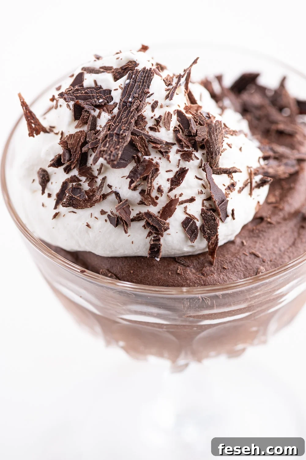 Sugar-free chocolate mousse in a glass dish with a dollop of whipped cream and dark chocolate shavings. 