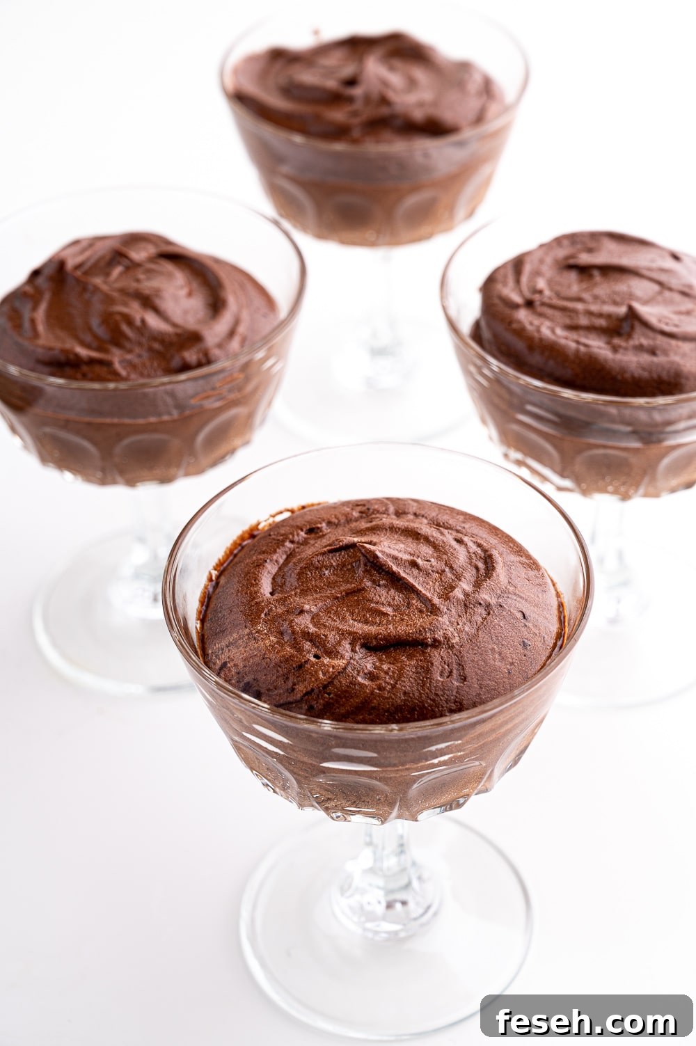 4 dishes of chocolate mousse against a bright white background. 