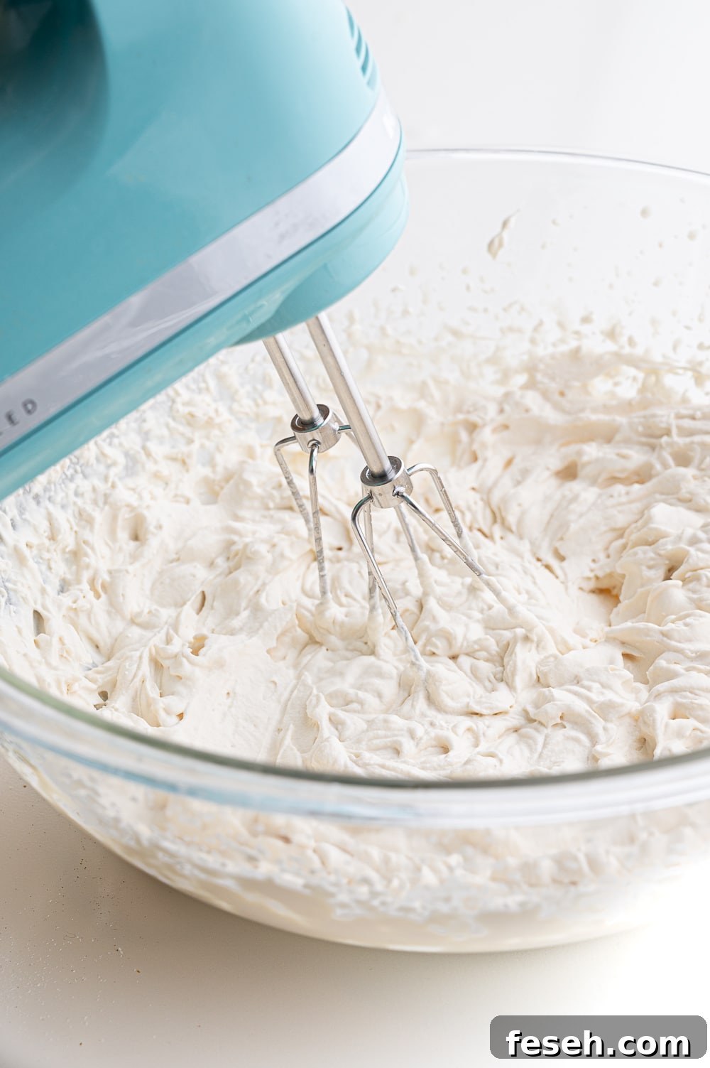 Whipped cream partially whipped in a glass bowl. 