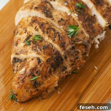 A close up image on a grilled chicken breast on a wooden cutting board.