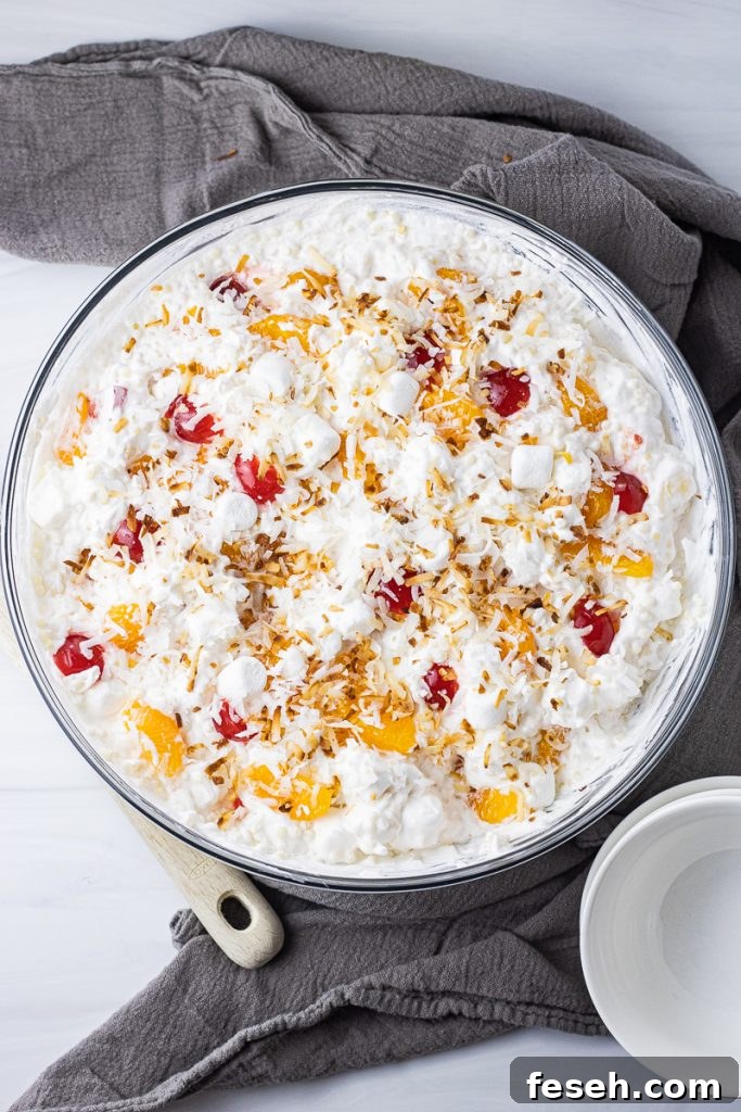 fluffy fruit salad with small pasta, oranges, cherries and topped with toasted coconut