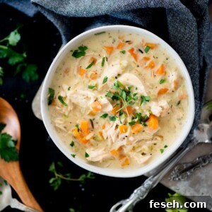 Creamy chicken and rice soup in a bowl topped with parsley and thyme