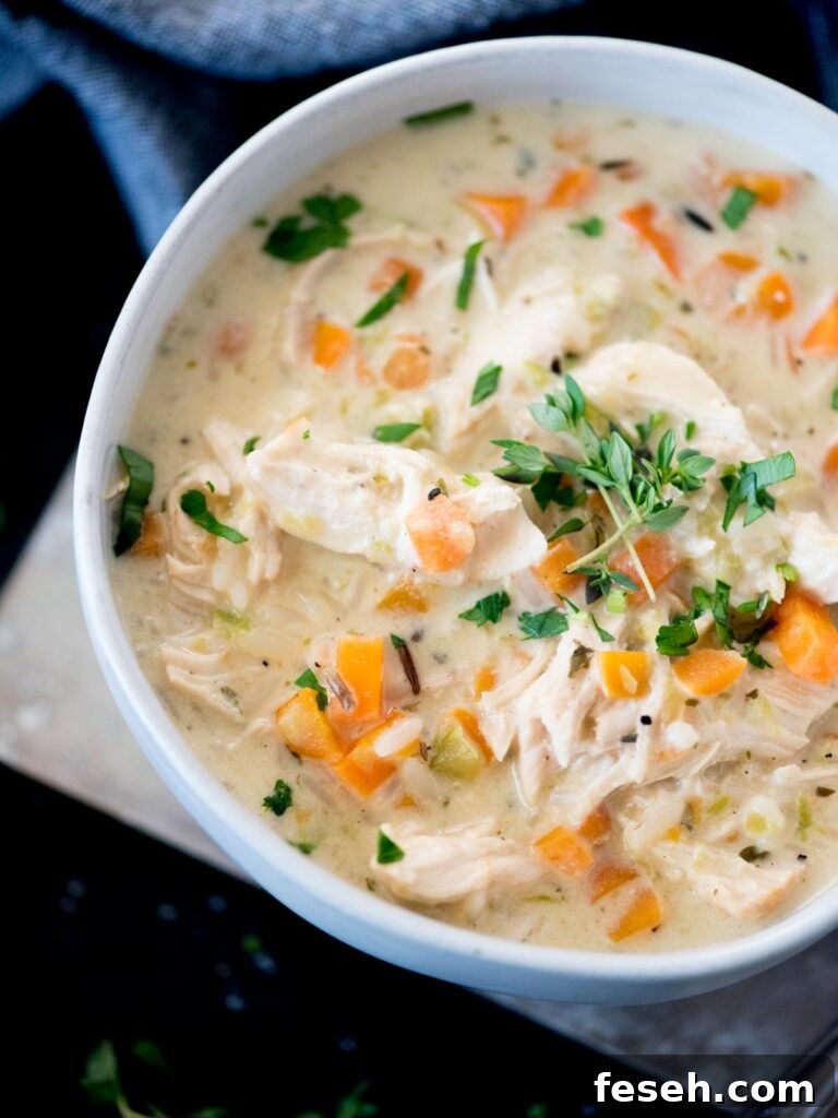 Creamy chicken and rice soup in a bowl topped with parsley and thyme