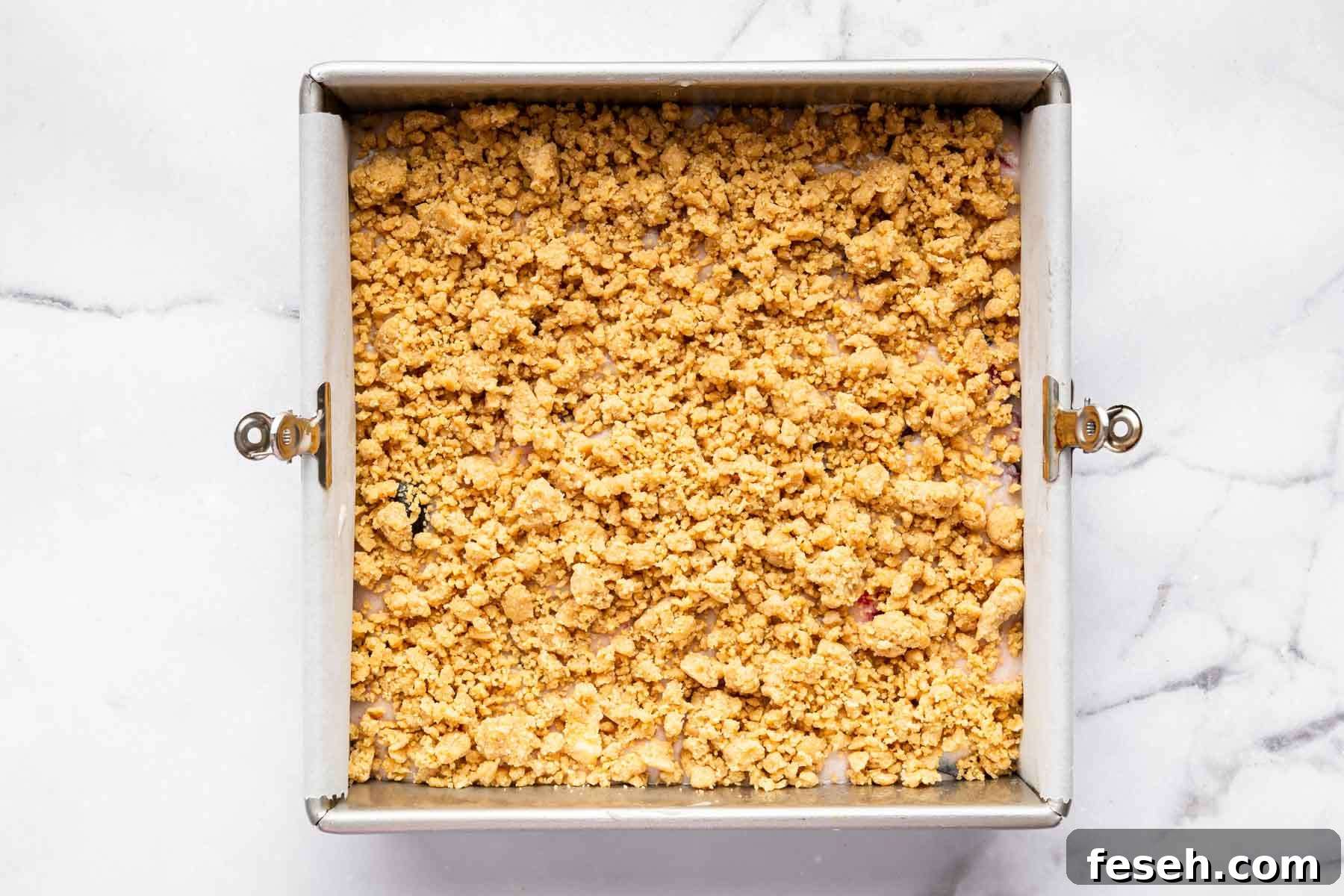 Square dessert with big streusel chunks on top before baking.