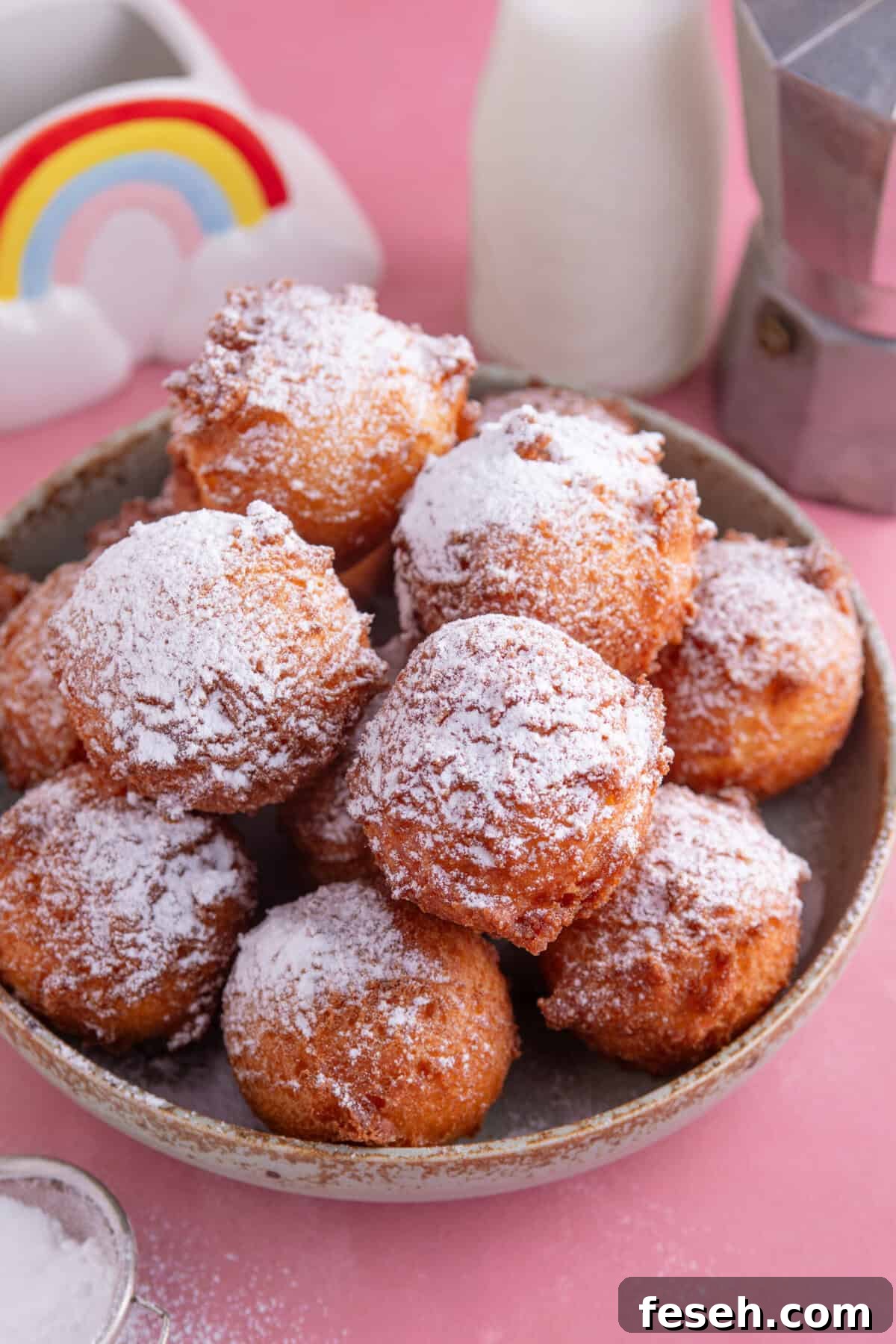 A bowl of gluten free zeppole dusted with icing sugar.