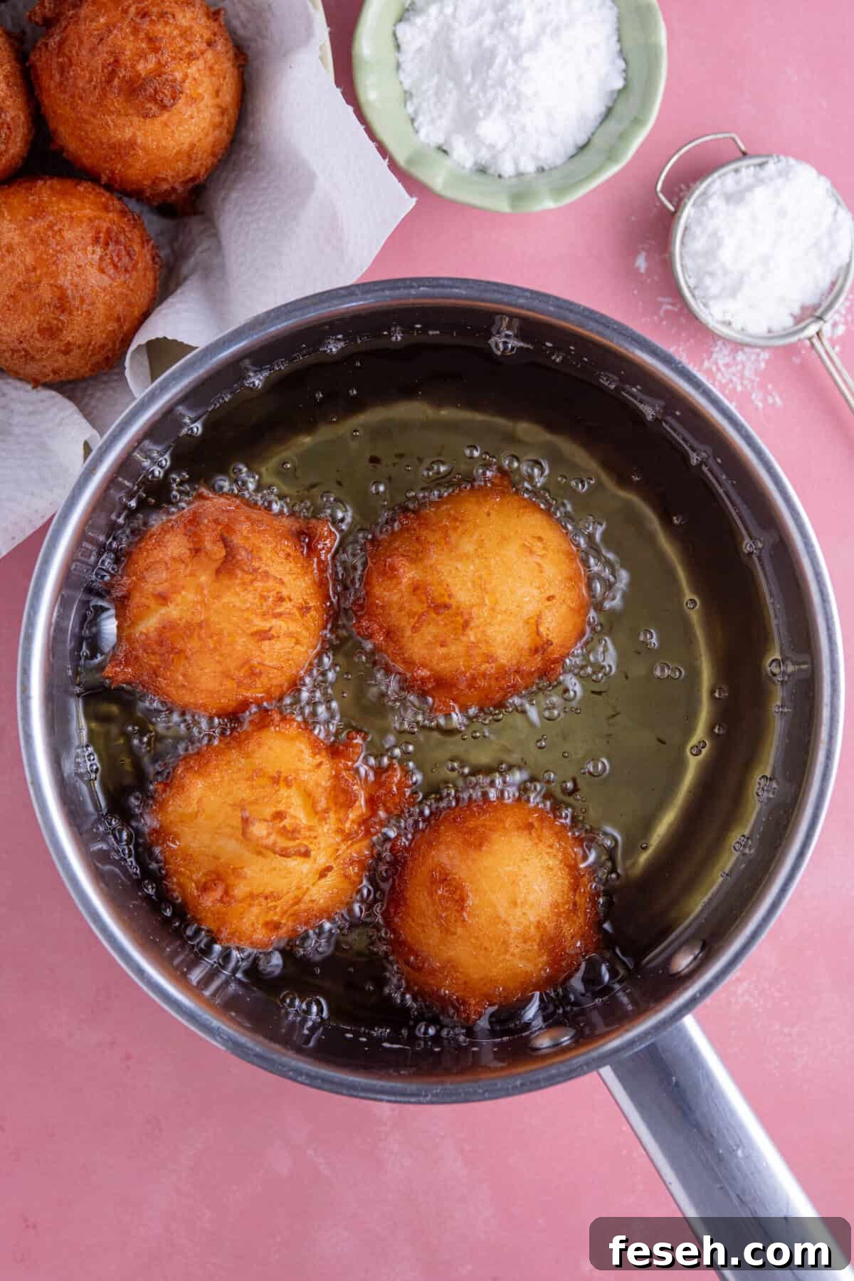 Process shot for gluten free zeppole showing the dough deep frying in a pan of oil.