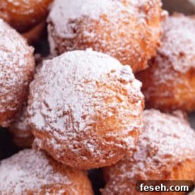 Close up of gluten free zeppole - fried doughnut balls dusted in icing sugar.