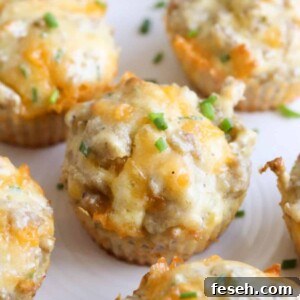 Several sausage cheese muffins arranged on a white plate, topped with sliced chives