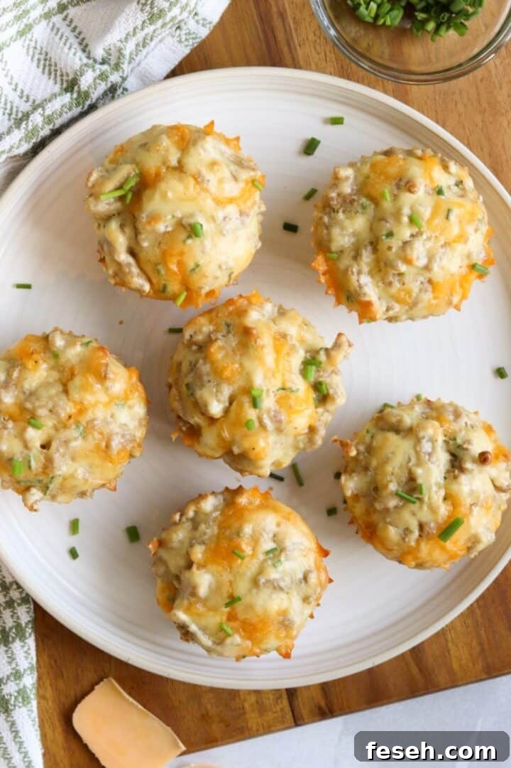 Overhead photo of sausage cheese muffins on a white plate, garnished with sliced chives