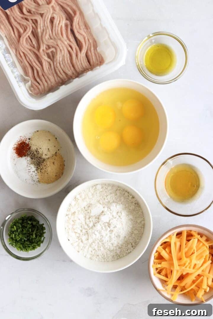 Ingredients for sausage cheese muffins displayed in small bowls on a white kitchen counter