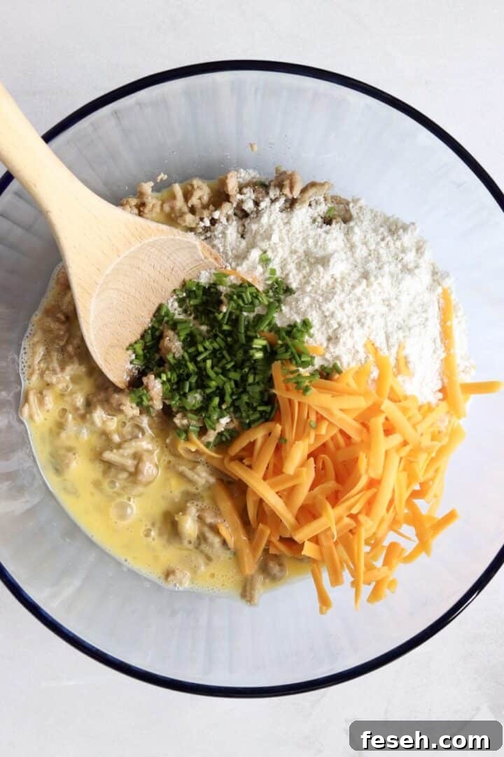 Ingredients for sausage egg muffins in a large glass bowl, unmixed
