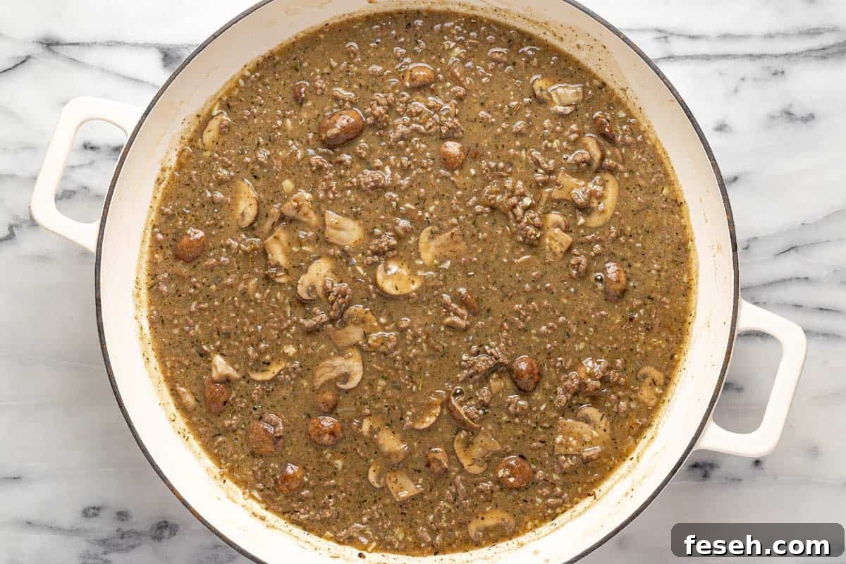 Large pan filled with ingredients to make beef stroganoff sauce. 