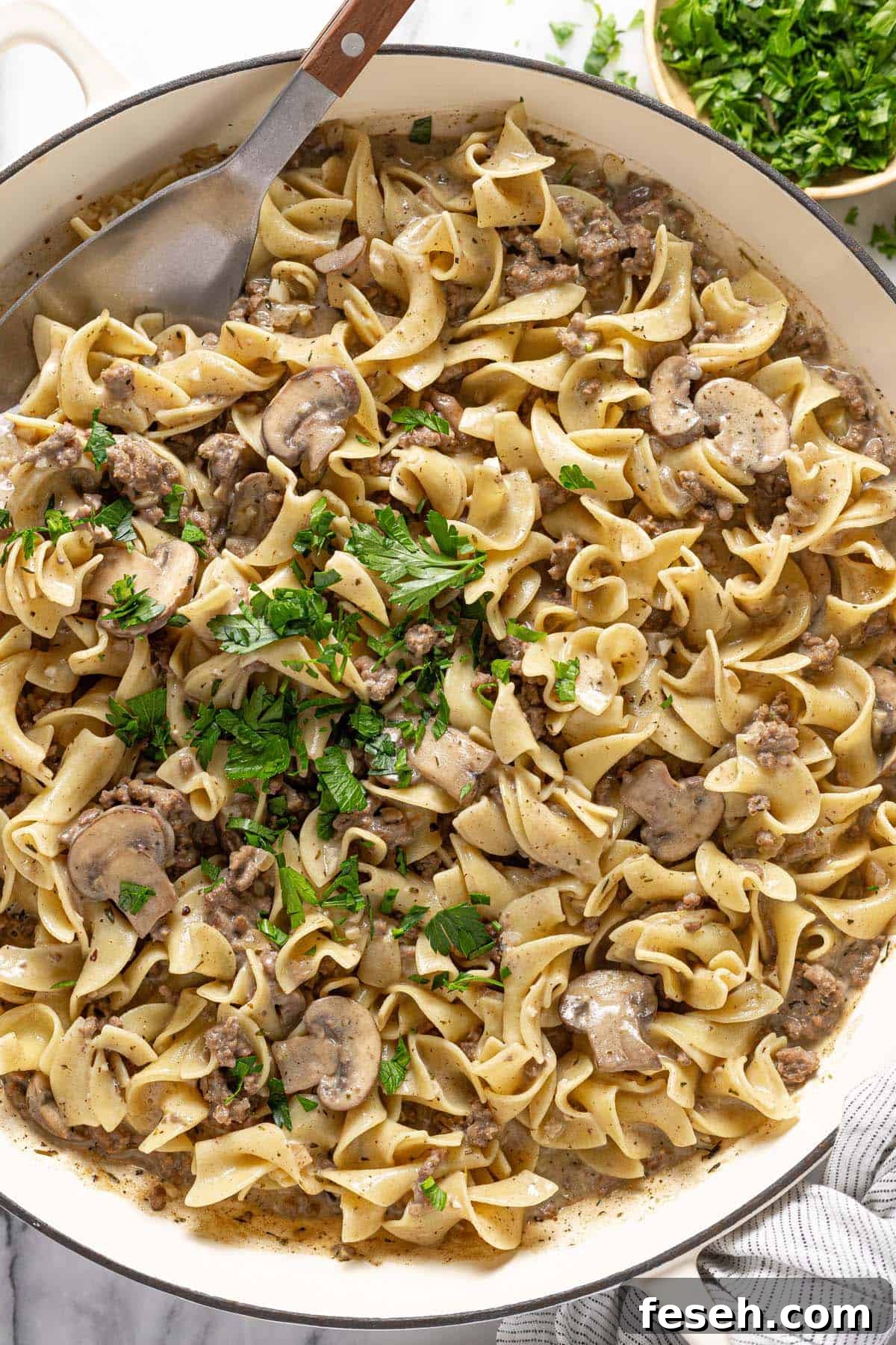 Ground beef stroganoff with egg noodles garnished with fresh parsley. 