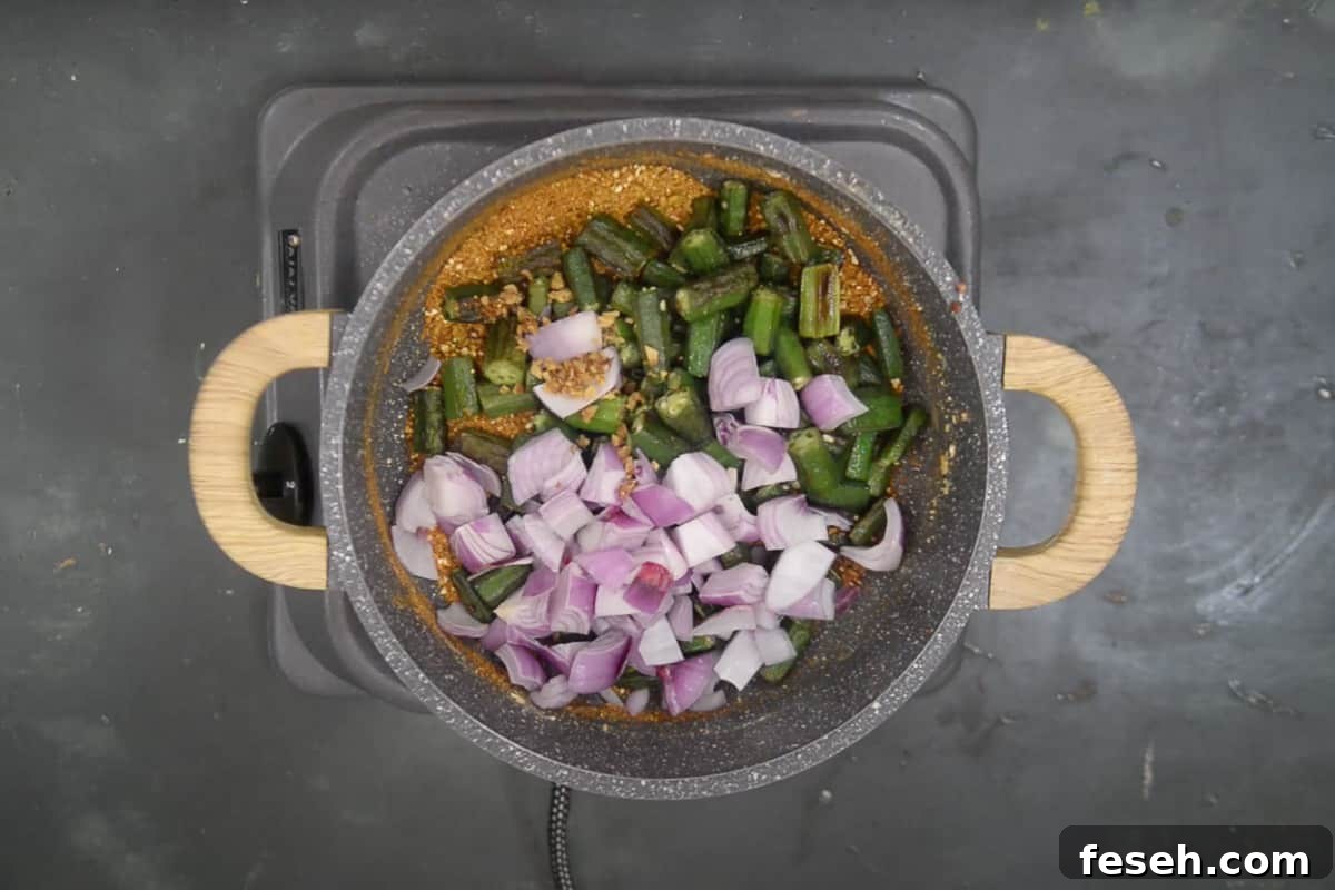 Fried bhindi, onion and ginger added in the pan.