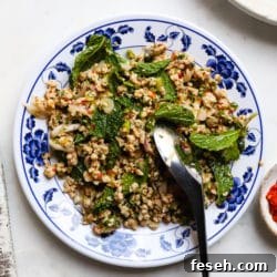 Plate of Thai chicken larb with mint and chili on a floral dish.