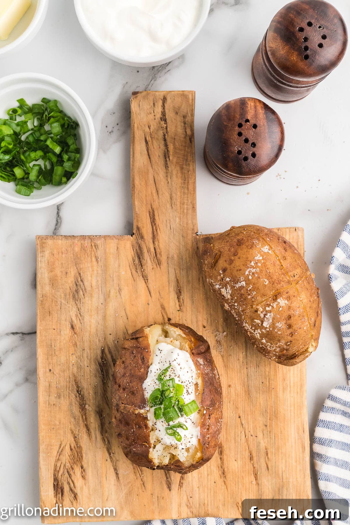 Smoked baked potatoes on a wooden board topped with sour cream and chives