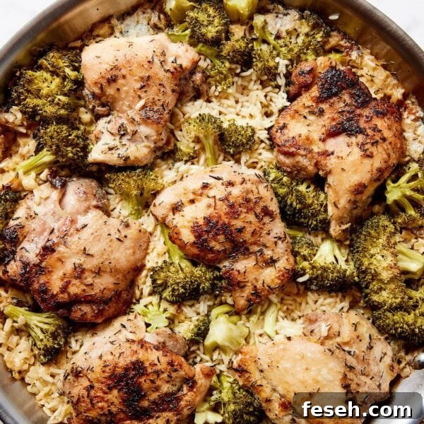 White marble surface with metal skillet with chicken, broccoli, and rice casserole inside.
