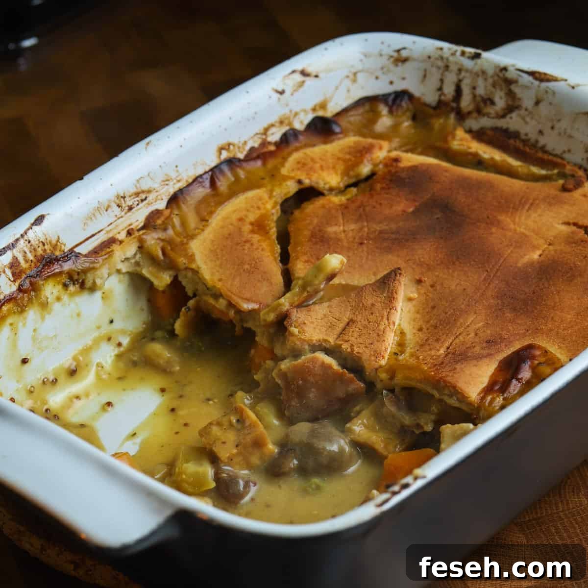 Photo of a casserole dish half served, with some filling spilling out from under the pastry.