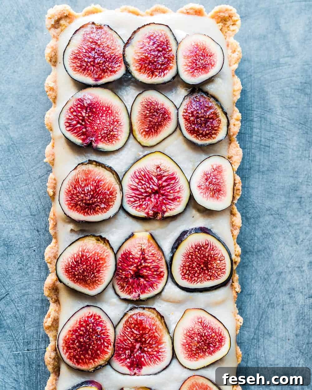 Full finished fig tart on blue-grey table.