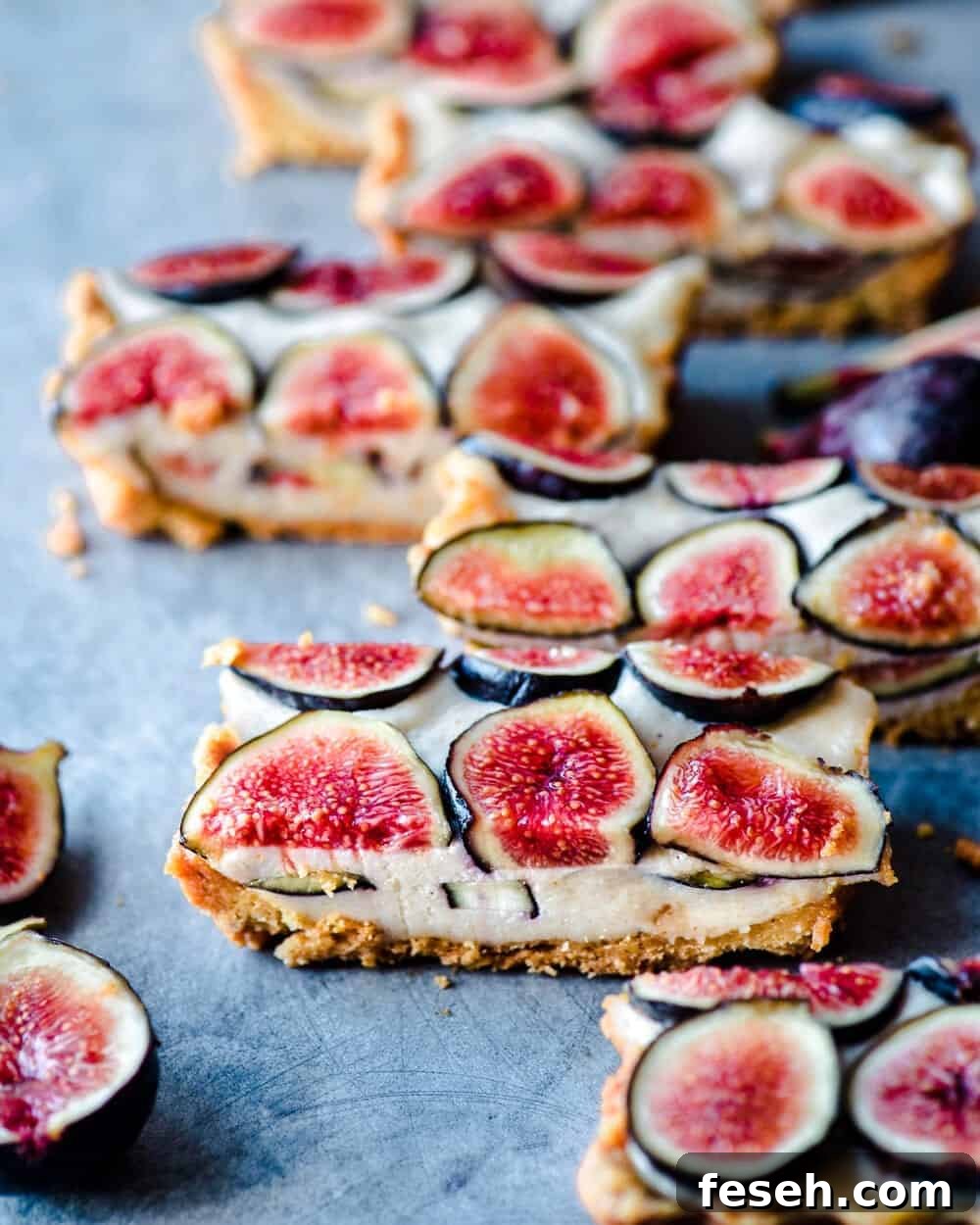 Side close up view of slices of fig tart on blue-grey table.