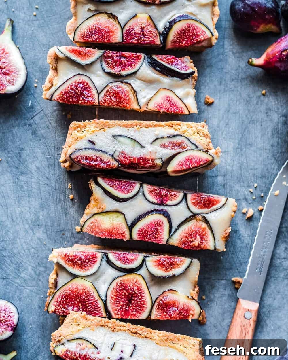 Slices of fig tart next to knife and figs on table.