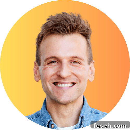 Kaleb Wyse standing in front of yellow and orange ombre background in a blue denim shirt.