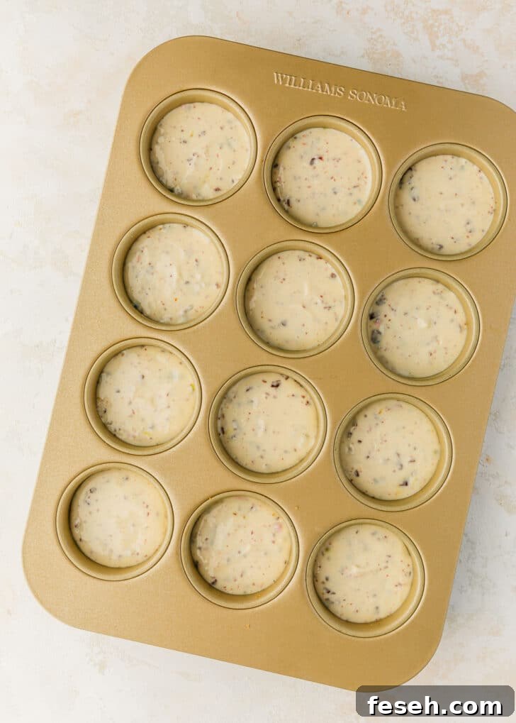 A pan of raw mini egg cheesecakes on a white and beige counter.