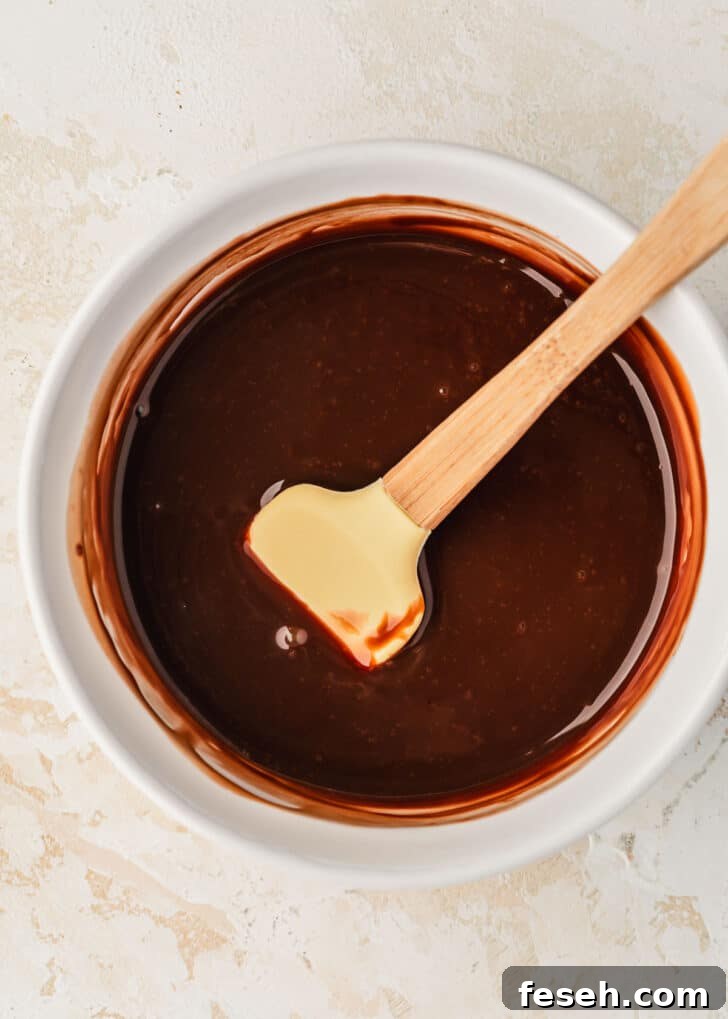 A white bowl of chocolate ganache on a beige table.