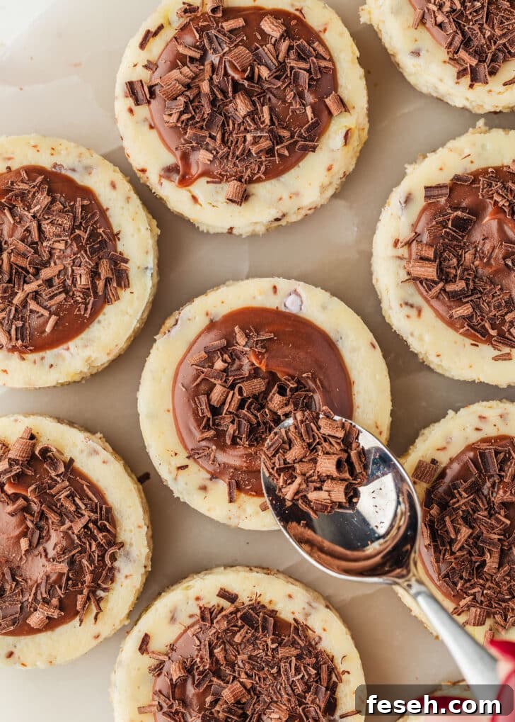 A hand using a spoon to top mini egg cheesecakes with chocolate curls.