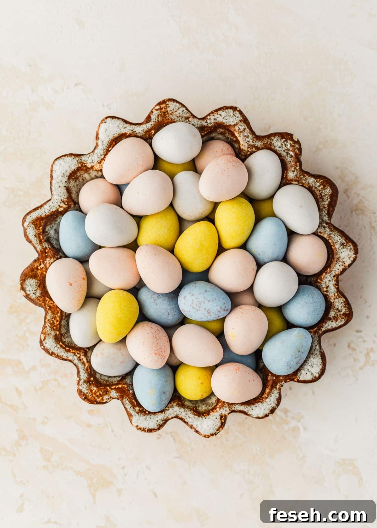 A brown and white bowl of egg candies on a beige counter.