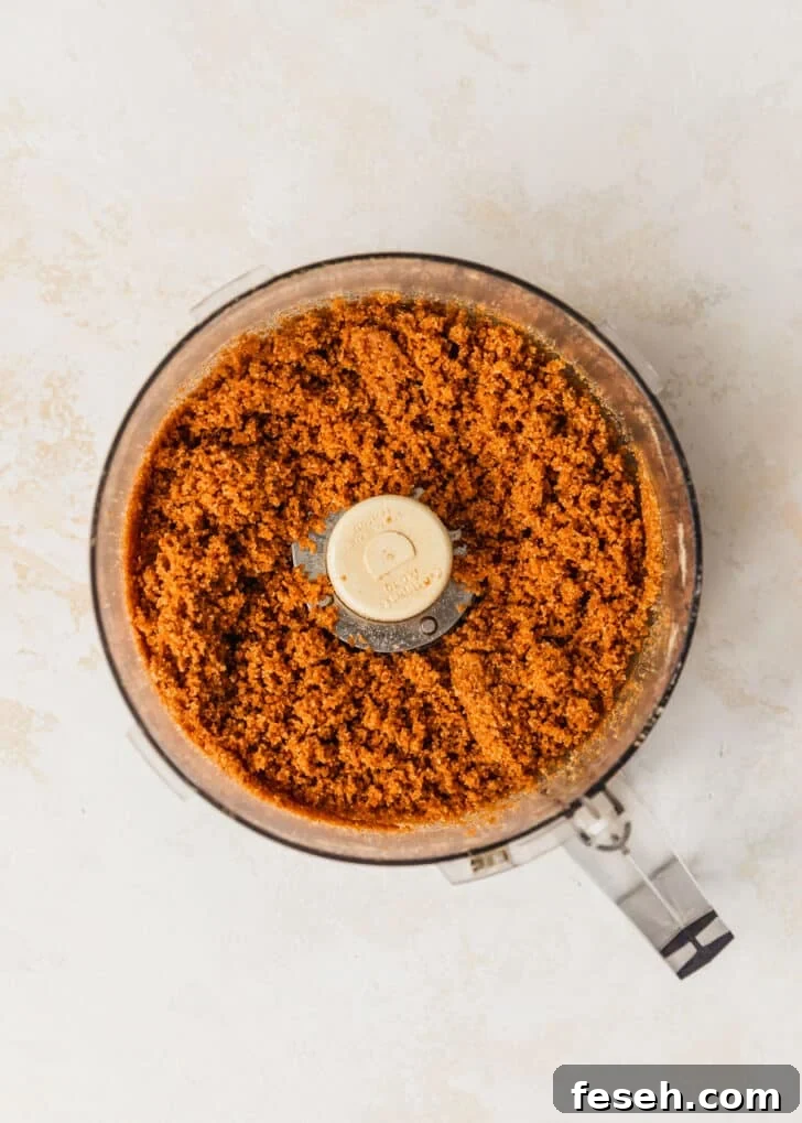 A food processor of graham cracker crust on a tan counter.