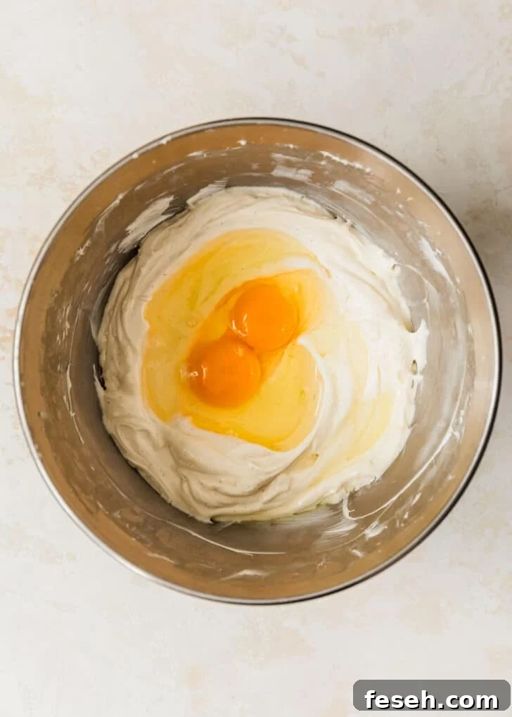 A silver bowl of cream cheese and eggs on a tan counter.