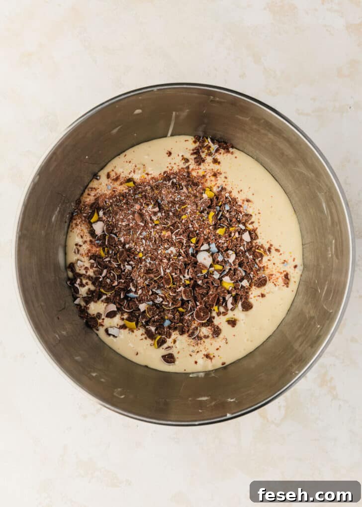 A silver bowl of filling for mini egg cheesecakes on a beige table.