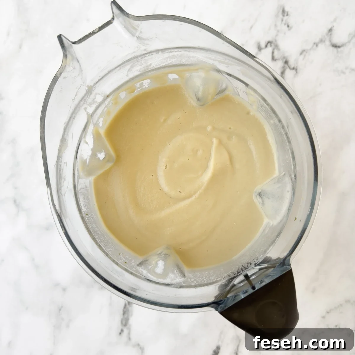 Blender container full of pureed pale colored creamy fennel soup.